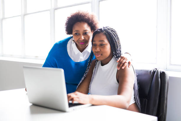 A Mother And Teenage Daughter Looking At Laptop Together A Mother And Teenage Daughter Looking At Laptop Together